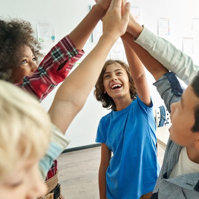 Five students standing in a circle high fiving